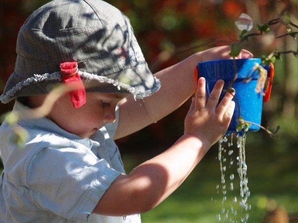 small child holding a flower pot leaking water